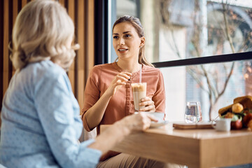 Mid adult woman drinking coffee and talking to her mother in cafe.