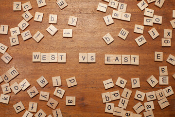 west versus east letters on wooden background