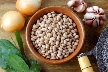 Raw carioca beans in bowl over rustic wooden table. Product name in Brazilian Portuguese