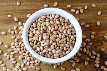 Raw carioca beans in bowl over rustic wooden table. Product name in Brazilian Portuguese