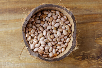 Raw carioca beans in bowl over rustic wooden table. Product name in Brazilian Portuguese