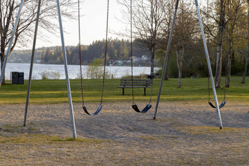 swing set in a park with a lake in the distance