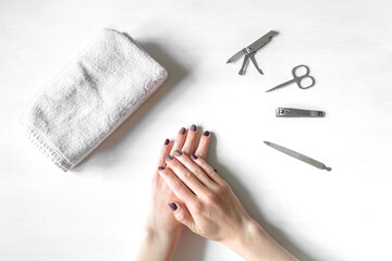 Closeup of hands with polished nails and manicure instruments. Young caucasian woman receiving homemade french manicure at nail salon. manicure, selfcare, beauty procedures yourself