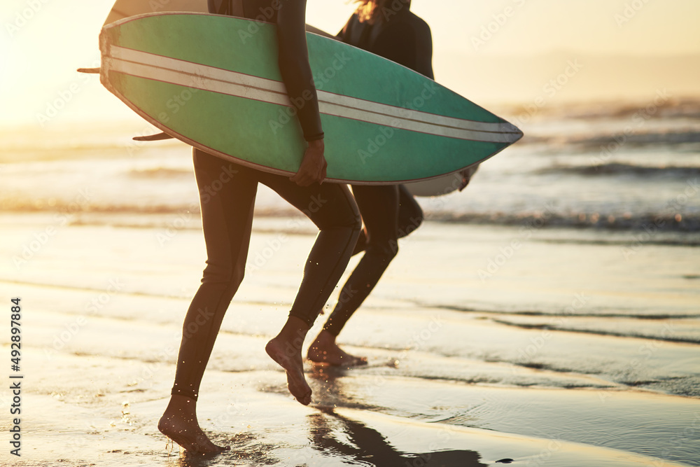 Sticker Life is an adventure, live it. Shot of an unrecognizable young couple going surfing at the beach.