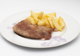 An Iberian secret, it is a highly appreciated pork meat in Spain. As a garnish some homemade chips, served on a plate. Isolated on white background.