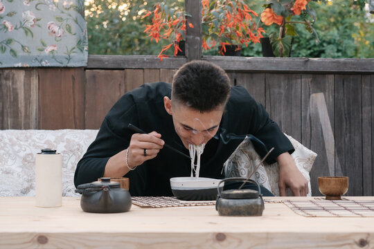 Young asian man dines noodles in a restaurant