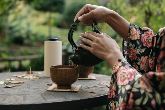 A young woman pours tea into a cup in the garden