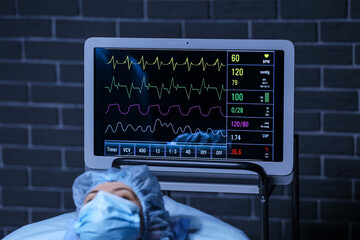 Patient lying near modern heart rate monitor in operating room