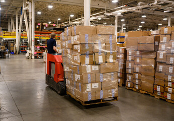 Forklift driver moving pallet of goods at warehouse 