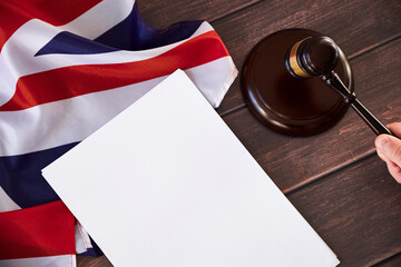 Fototapeta premium Gavel in judges hand, United Kingdom flag, blank list on wooden table. Law and justice concept.