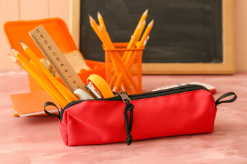 Red pencil case with different stationery on table