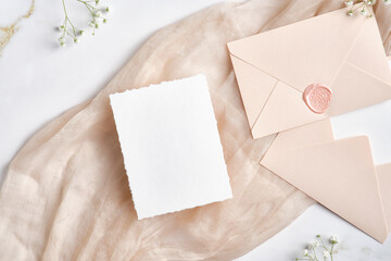 Blank white invitation card with pink envelopes and gypsophila branches. Wedding stationery set....