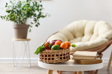 Table with fruit basket and books in light room