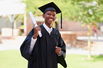 Its official. Portrait of a happy male student standing outside on his graduation day.
