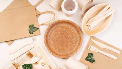 Recycling,eco-friendly concept.Disposable eco cutlery,plates,spoons,knives,forks on a light background.Craft paper bag for food delivery.Copy space.Eco craft paper tableware,cups,fast food containers.