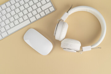 Background music or podcast with headphones and a computer keyboard on a beige table, flat. Top view, flat layout