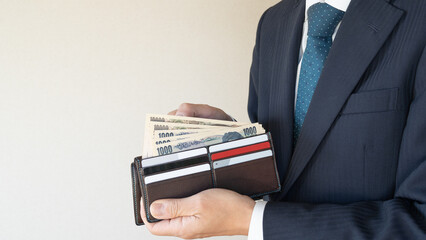 お金持ちのスーツ姿の男性｜日本の札束
