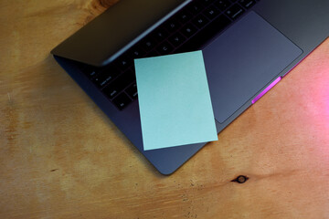 Green note reminder paper over laptop keyboard. Notebook message paper