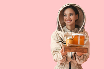 Female beekeeper with honey on color background