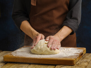 Chef or baker prepares dough for baking or bread, pizza, pasta. Cooking and cooking.On black background, advertisements for bakery or cooking recipes