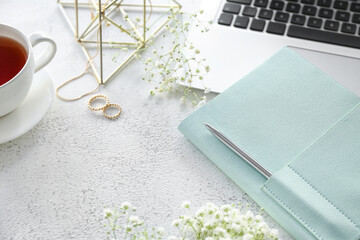 Stylish notebook with jewelry, gypsophila flowers and laptop on grunge background, closeup