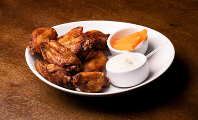 chicken wings in buffalo sauce with carrots and cream cheese on wooden table