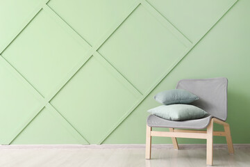 Modern armchair with pillows near color wall