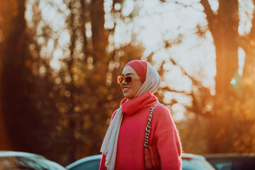 A Muslim woman wearing a hijab walks the streets of the city in a modern outfit combined with sunglasses. Selective focus