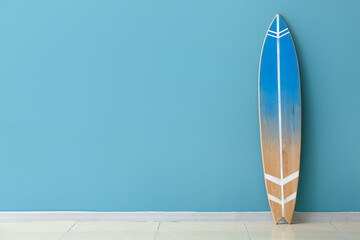Modern surfboard near color wall in room