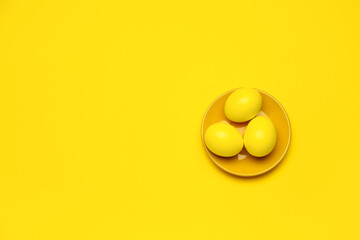 Plate with Easter eggs on yellow background