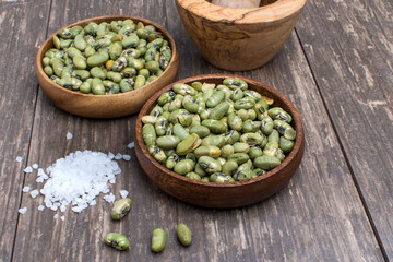 delicious roasted salty green bean seeds in a wooden bowl on a  table
