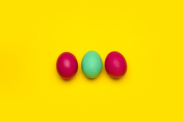 Three colorful Easter eggs on yellow background