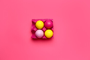 Holder with painted Easter eggs on color background