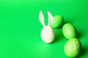 Creative composition with painted Easter eggs and rabbit ears on color background