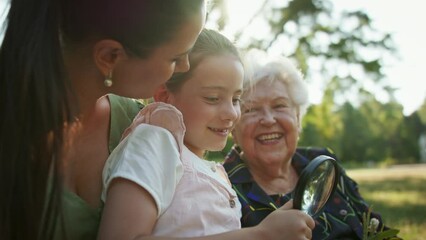 Small girl with mother and grandmother resting in a park, talking. - Powered by Adobe