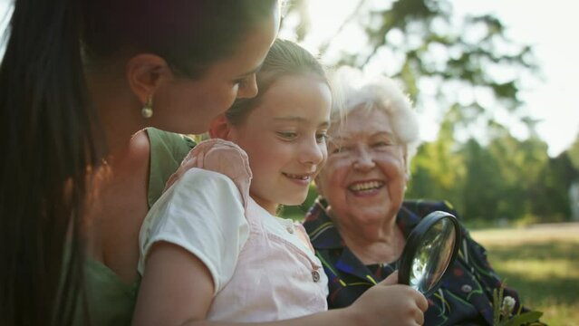 Small girl with mother and grandmother resting in a park, talking.