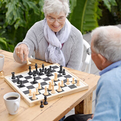 This next moves is going to win me the game. An elderly couple playing chess together outdoors.