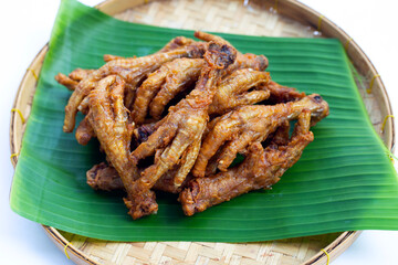 Fried chicken feet in bamboo basket on white background.