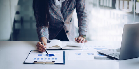 Close up Business woman hand using calculator to calculate the company's financial results and...