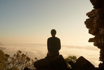 Solitude at sundown. Shot of a woman admiring the view from a mountain top.