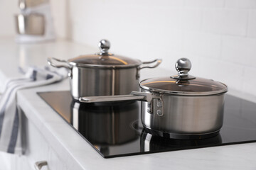 New clean pot and saucepan on cooktop in kitchen - obrazy, fototapety, plakaty