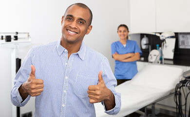 Cheerful Latino man happy with results of cosmetology procedures in clinic of aesthetic medicine,...