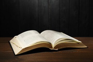 Open Bible on table against black wooden background. Christian religious book