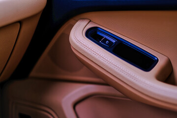 Luxury car beige colour leather interior details with power button to open window and side speaker. Car interior background and design element.