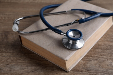 Student textbook and stethoscope on wooden table. Medical education