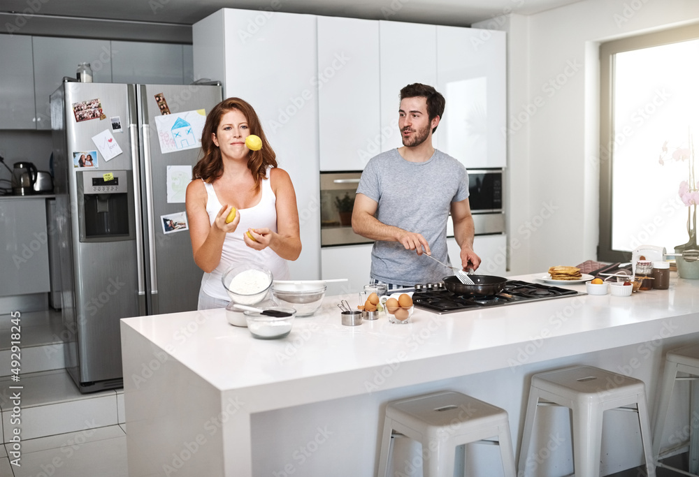 Poster Switching roles doesnt make a difference when united. Shot of a happy young couple preparing breakfast in the morning.