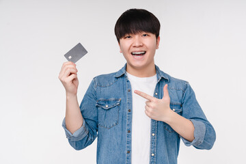 Offer discount sale. Happy funny young korean asian man boy student pointing at credit card for...