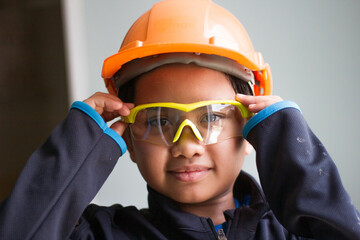 Asian boy dressed as a craftsman and holding tools	