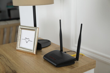 Modern Wi-Fi router on wooden table in room - obrazy, fototapety, plakaty
