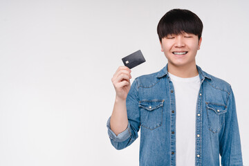 Asian korean young man boy student freelancer with eyes closed holding credit card making a wish...